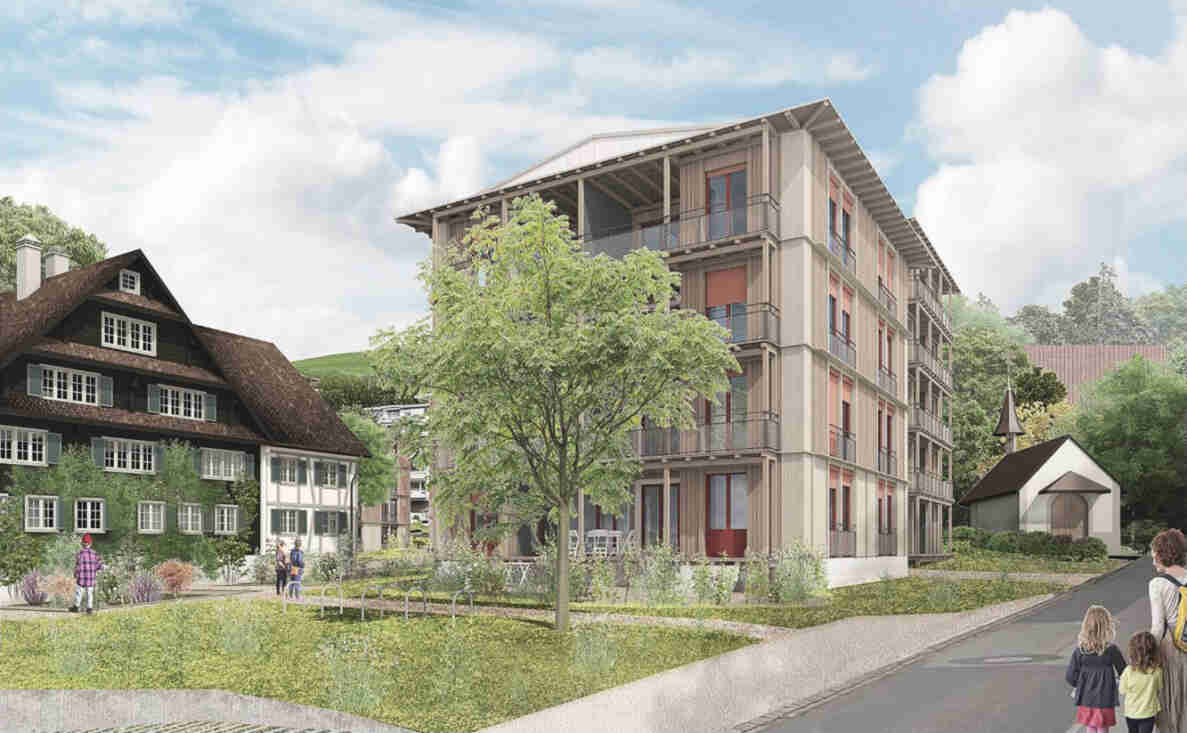 Visualisierung Talacher: mehrstöckiges Holzgebäude mit Balkonen neben traditionellem Riegelhaus und kleiner Kapelle. Grünfläche mit Bäumen, Sträuchern und Veloständern im Vordergrund. Rechts ein schmaler Fussweg entlang einer ruhigen Quartierstrasse ohne Verkehrssignale. Mehrere erwachsene und kindliche Personen bewegen sich zu Fuss auf dem Weg und der Wiese.