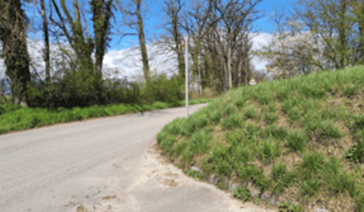 Kurvige Nebenstrasse in Walperswil bei der Einmündung Stockmattweg (rechts, hinter der Kuppe der Böschung). Die Sichtverhältnisse auf die einmündende Strasse sind durch die Böschung mit Gras eingeschränkt. Fahrbahnrand mit Bankett, keine Gehwegtrennung für Fussgänger. Ein Verkehrsschild ist am Strassenrand erkennbar, weitere Signalisation nicht eindeutig sichtbar. Keine Personen oder Fahrzeuge auf der Strasse erkennbar.